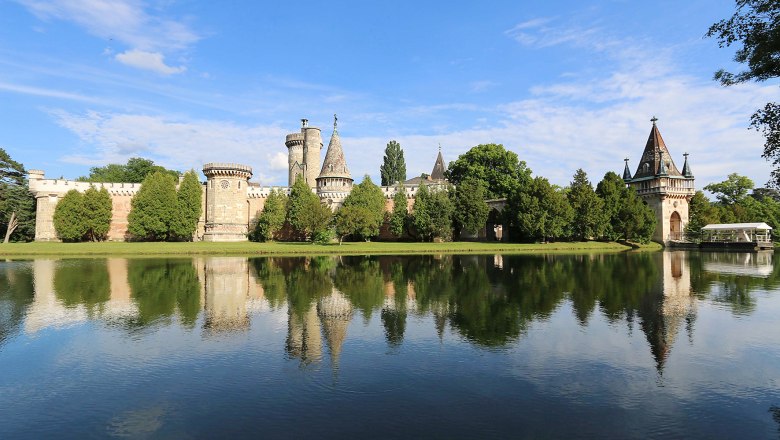 Schlosspark Laxenburg mit Wassergraben und Schloss im Hintergrund.