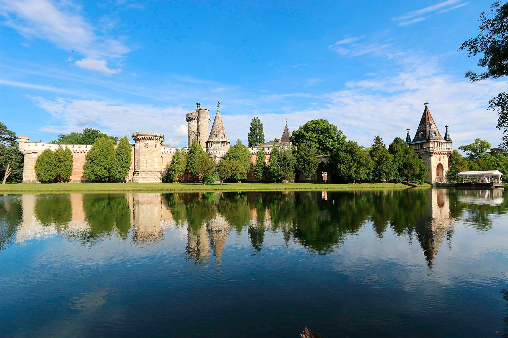 Schlosspark Laxenburg mit Wassergraben und Schloss im Hintergrund.
