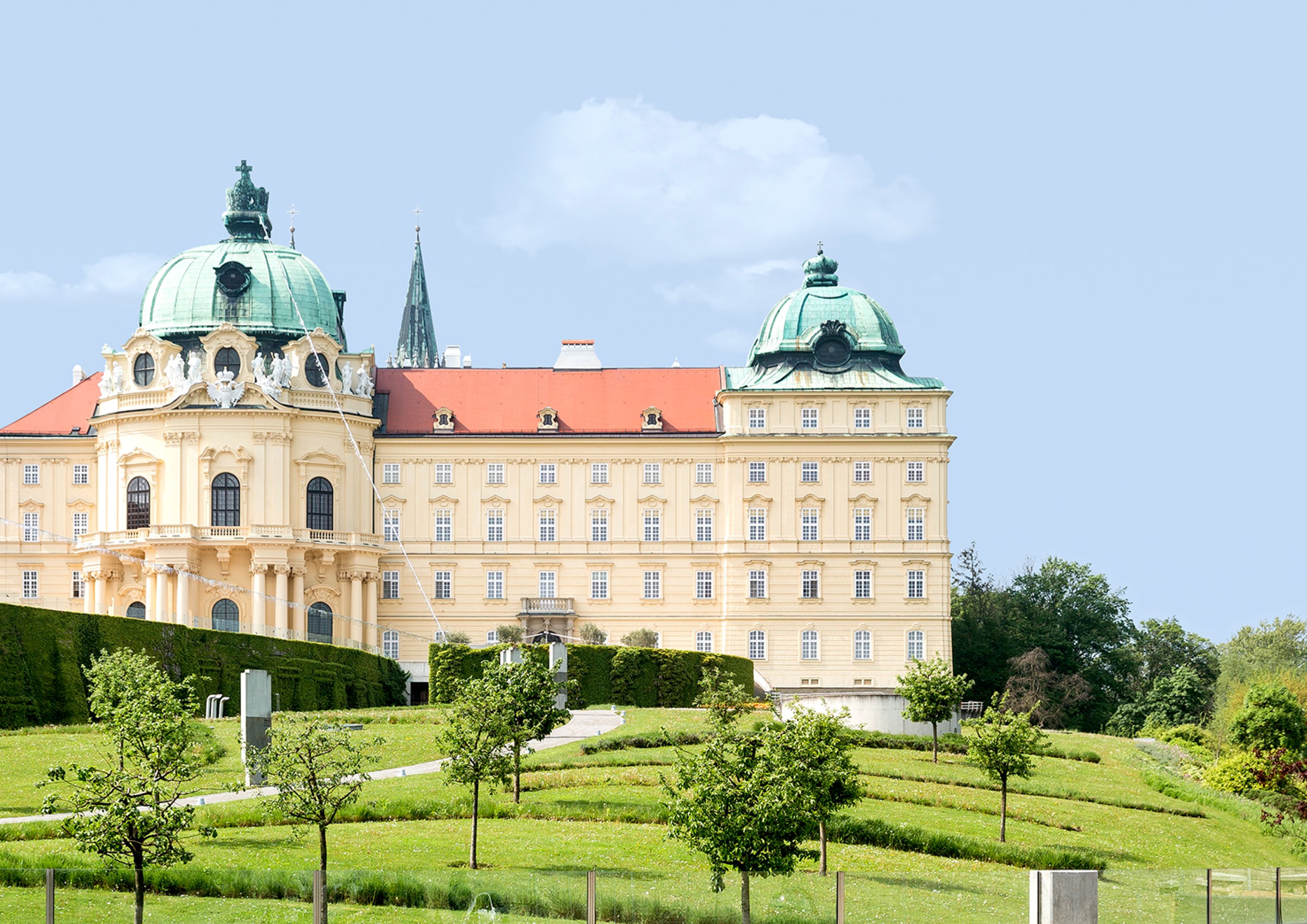 Stift Klosterneuburg mit grünen Kuppeln und gepflegtem Garten im Vordergrund.
