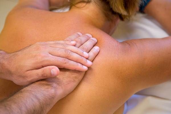 Nahaufnahme einer Massage, bei der Hände den Rücken einer Person massieren.